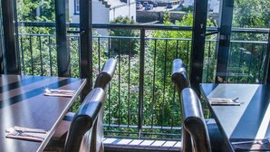 Un balcon offrant une vue sur la mer et les bâtiments, avec un plancher en bois et des rampes en métal.