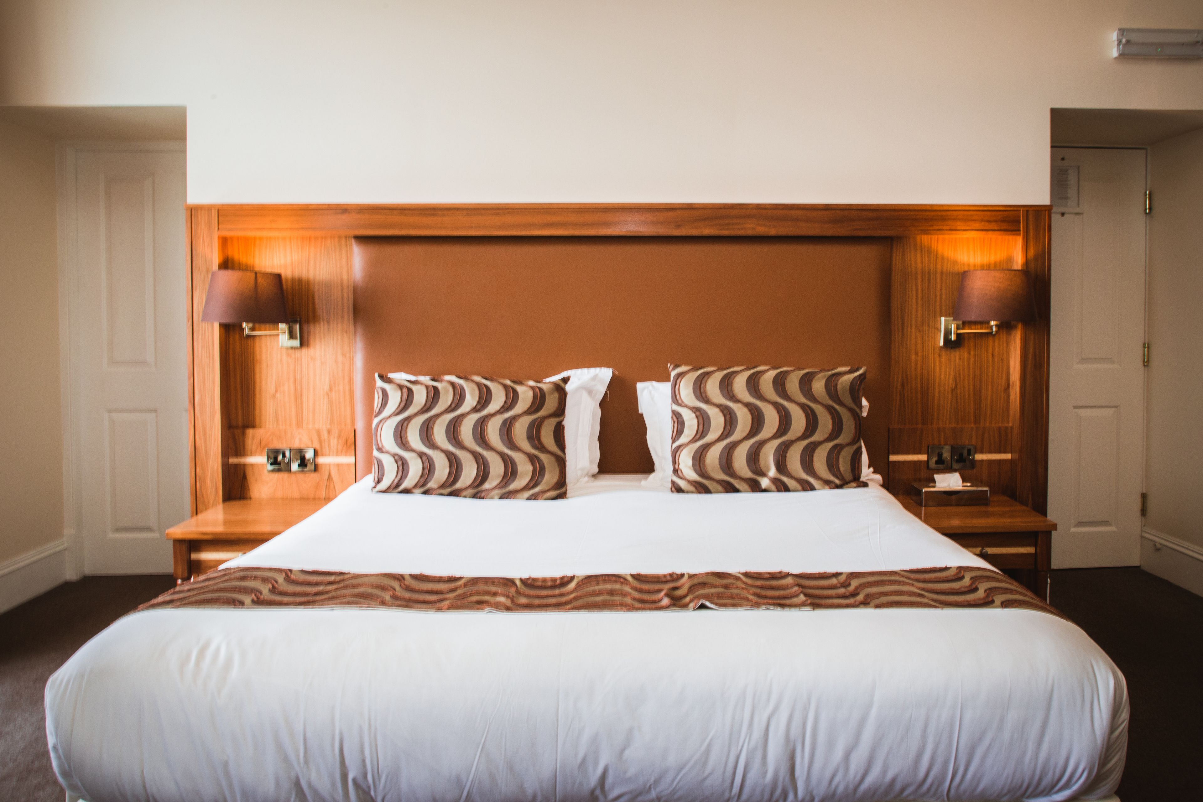 Ein Hotelzimmer mit einem großen Bett, zwei Nachttischen und einem hölzernen Kopfteil.