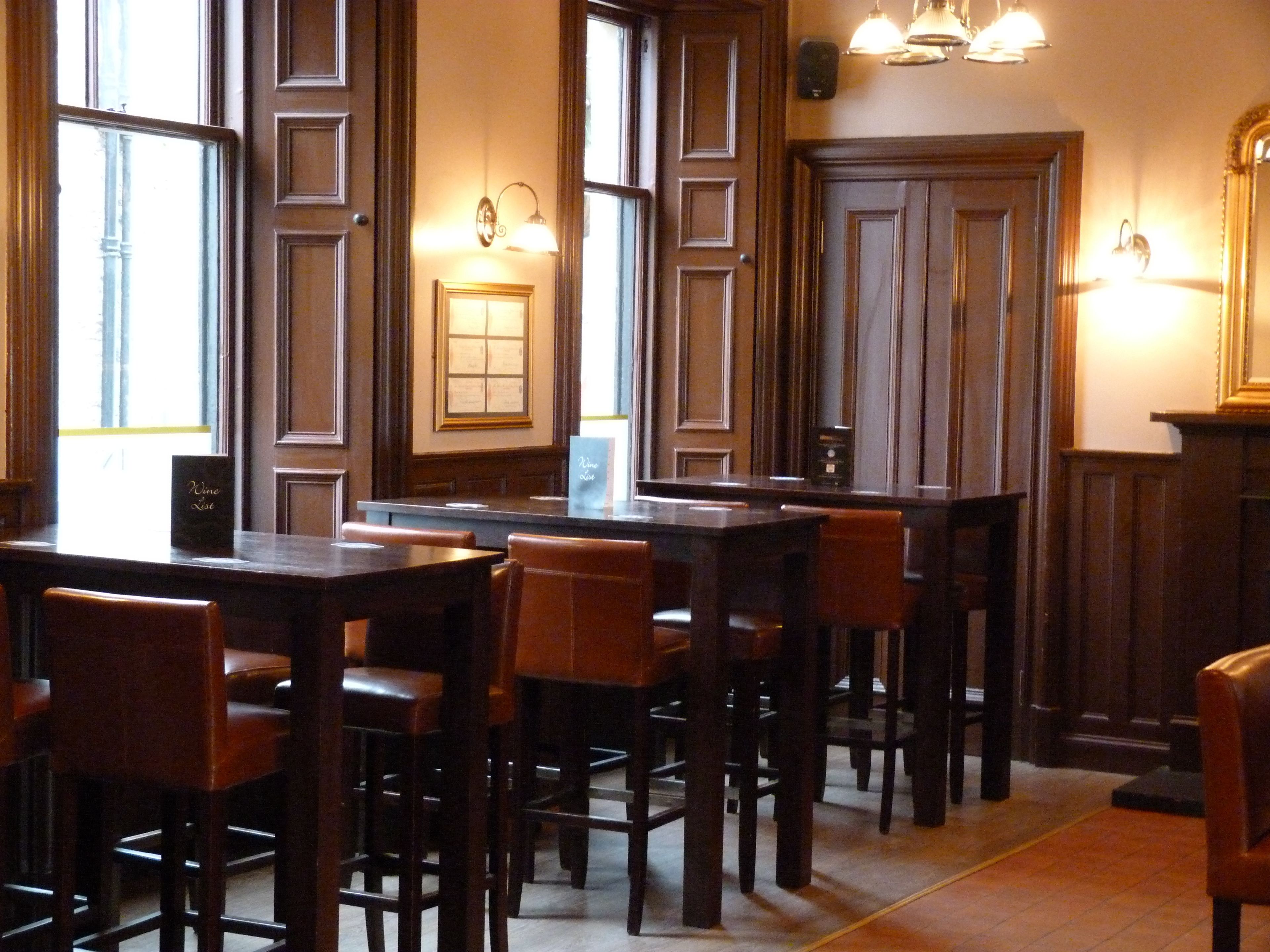 Ein Restaurant mit Holztischen und -stühlen, einer Speisekarte und Wandleuchten.