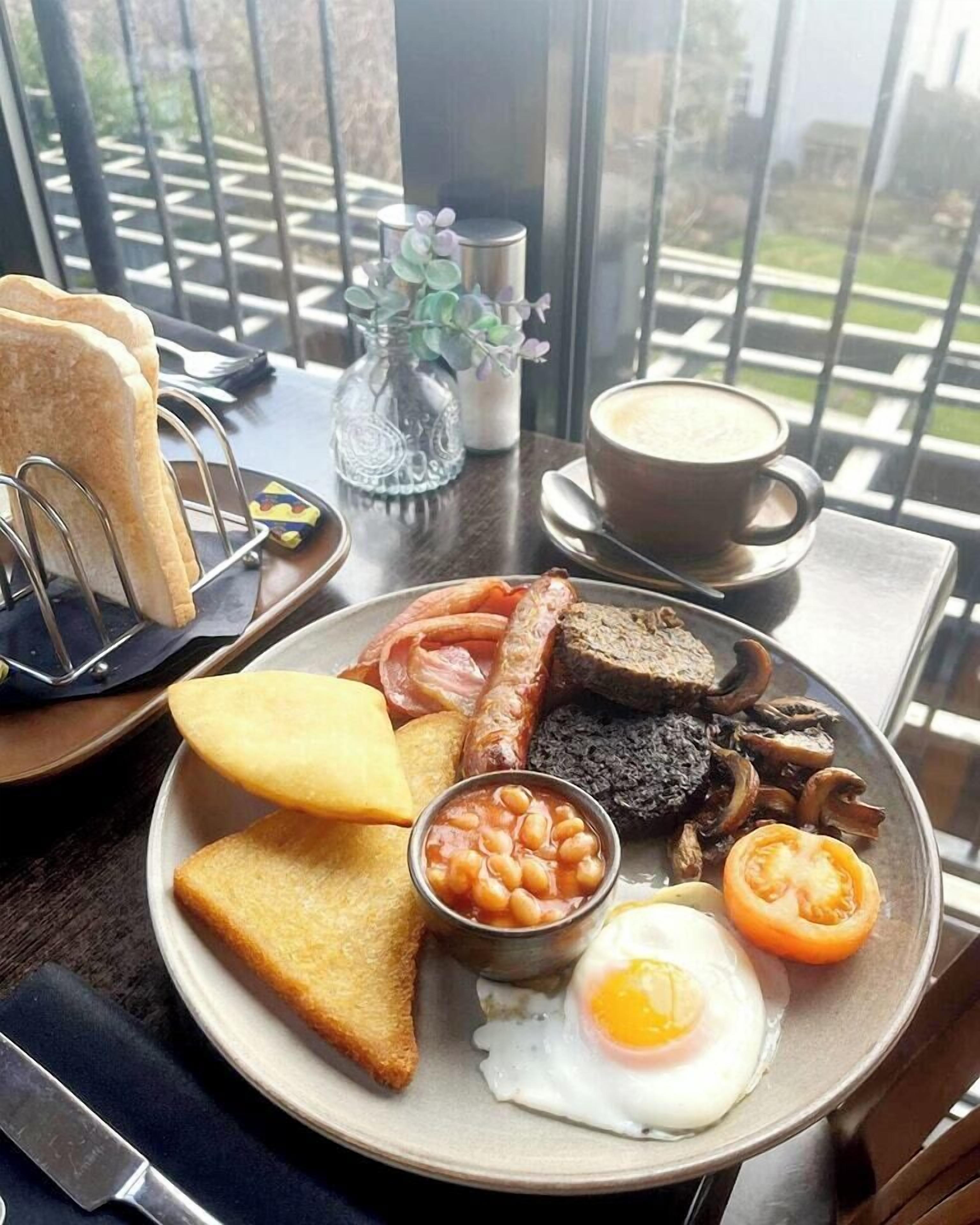 A breakfast plate with toast, beans, eggs, mushrooms, and tomatoes.