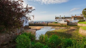 Un village côtier aux maisons blanches traditionnelles, avec un petit étang et un espace de stationnement pour voitures.