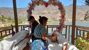 A massage therapy area with two massage tables, a floral arch, and a scenic lake view.