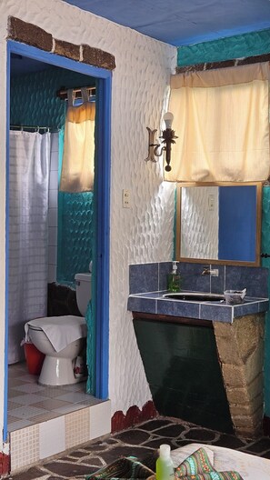 A bathroom with a toilet, sink, and mirror. - Eco Hotel Uxlabil Atitlan (San Juan La Laguna)
