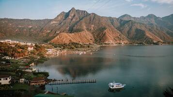 A lake with mountains in the background, a dock, and a boat.