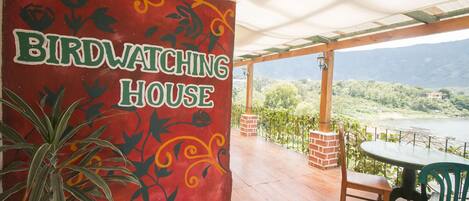 A birdwatching house with a red wall featuring bird silhouettes and the text "BIRDWATCHING HOUSE".