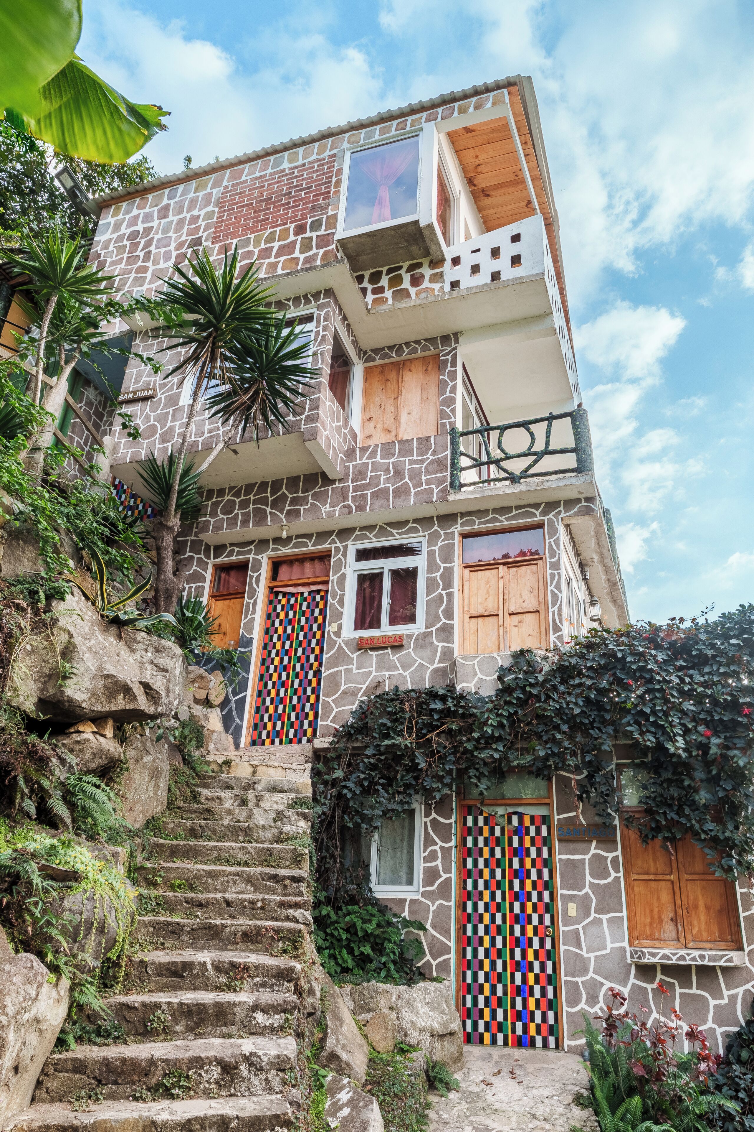 A multi-story building with a stone facade, a staircase leading to the entrance, and a balcony.