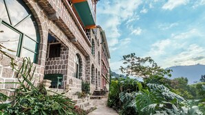 A stone building with a green awning, a stone staircase, and lush greenery.