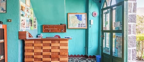 A reception desk with a wooden panel design, a map on the wall, and a green door with glass panels.