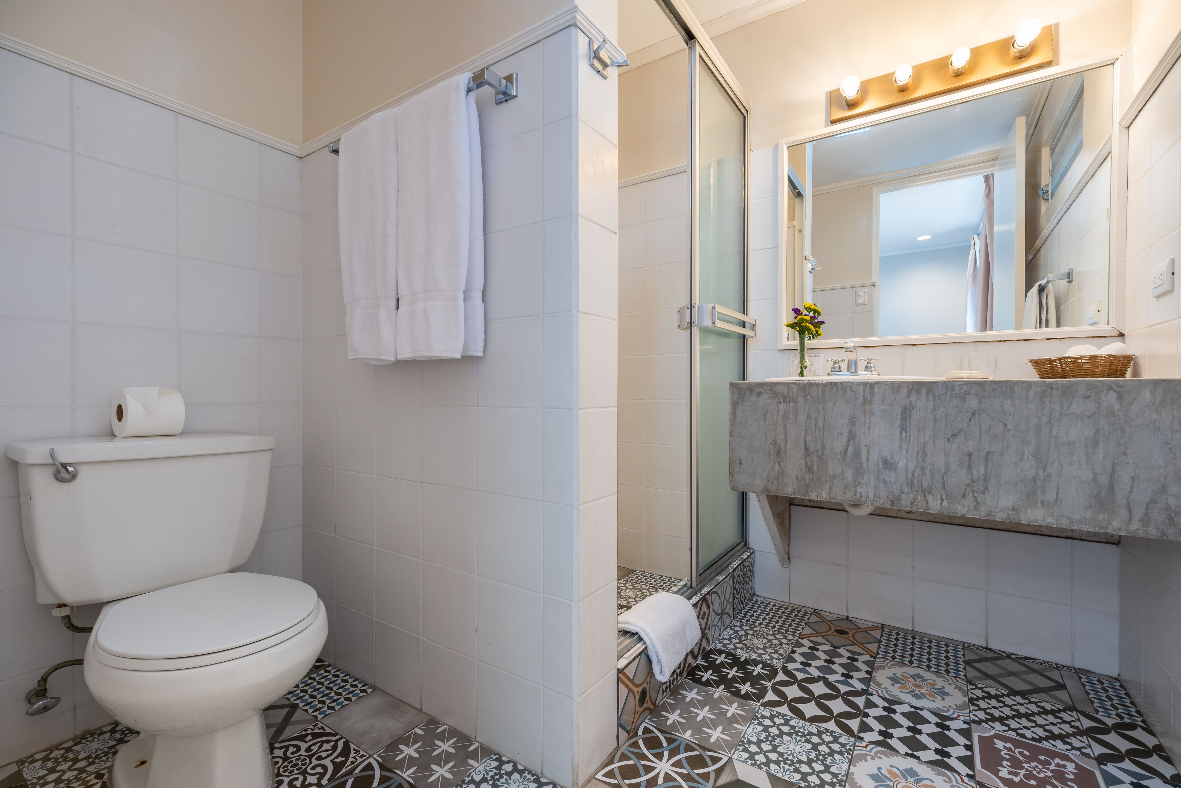Un baño con inodoro, ducha y tocador con espejo.