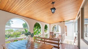 A wooden deck with a table and benches, overlooking a garden and a view of the city. - Posada El Quijote (San Rafael)