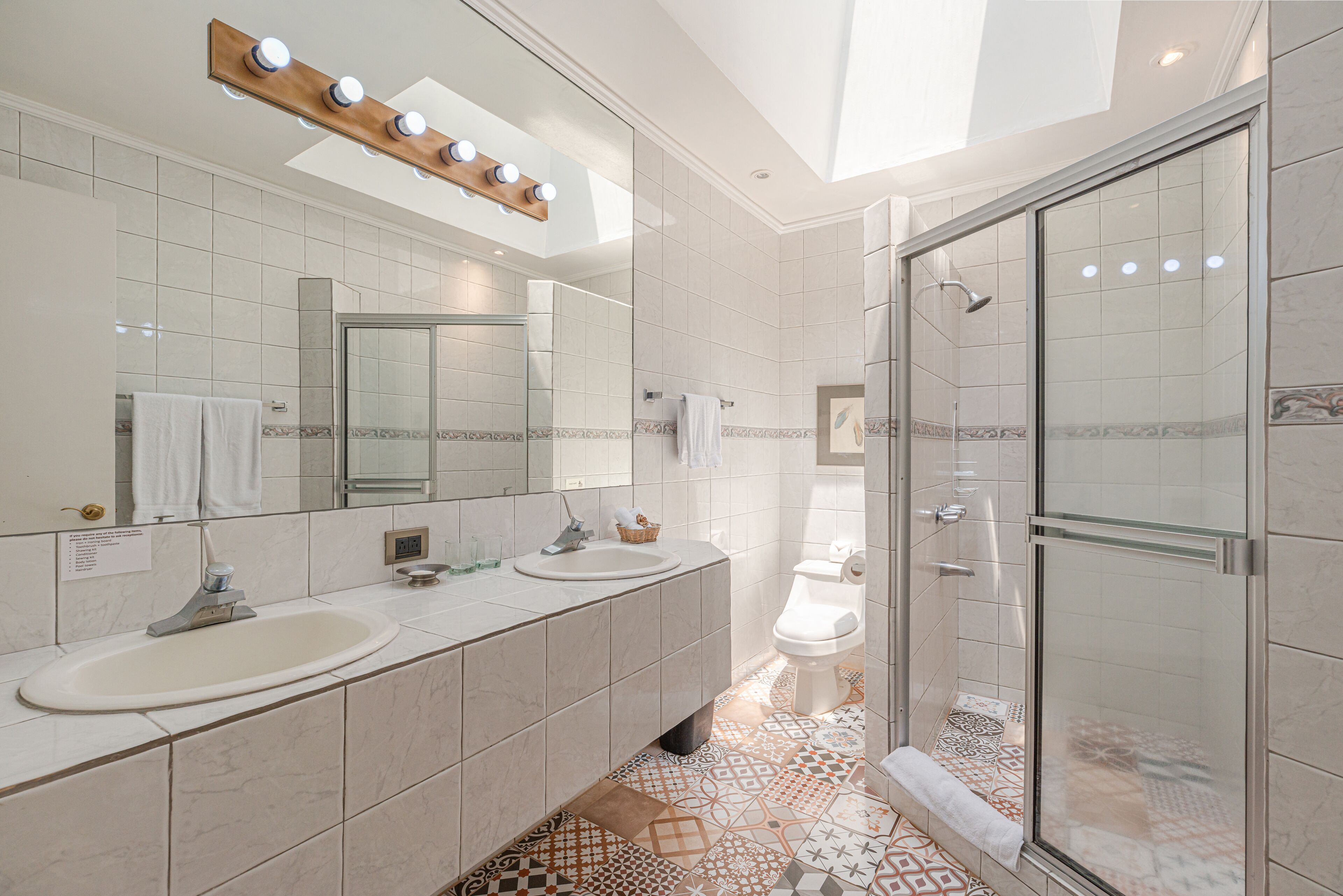 Un baño moderno con dos lavamanos, un espejo grande y una zona de ducha.