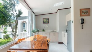 A modern kitchen with a wooden dining table, white cabinets, and a view of the outdoors. - Posada El Quijote (San Rafael)