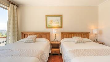 A hotel room with two beds, a nightstand with lamps, a painting on the wall, and a view through the window.