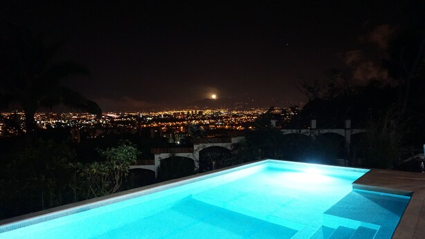 A swimming pool with a view of a cityscape at night. - Posada El Quijote (San Rafael)