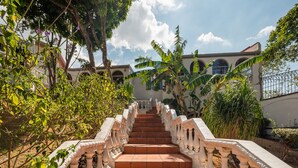 A staircase with white balustrades leading to a building with arched windows. - Posada El Quijote (San Rafael)