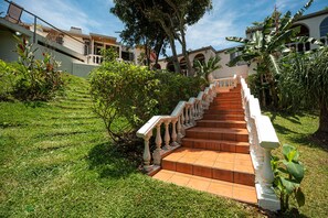 A staircase with white balustrades leading to a building with arched windows and a tiled roof. - Posada El Quijote (San Rafael)