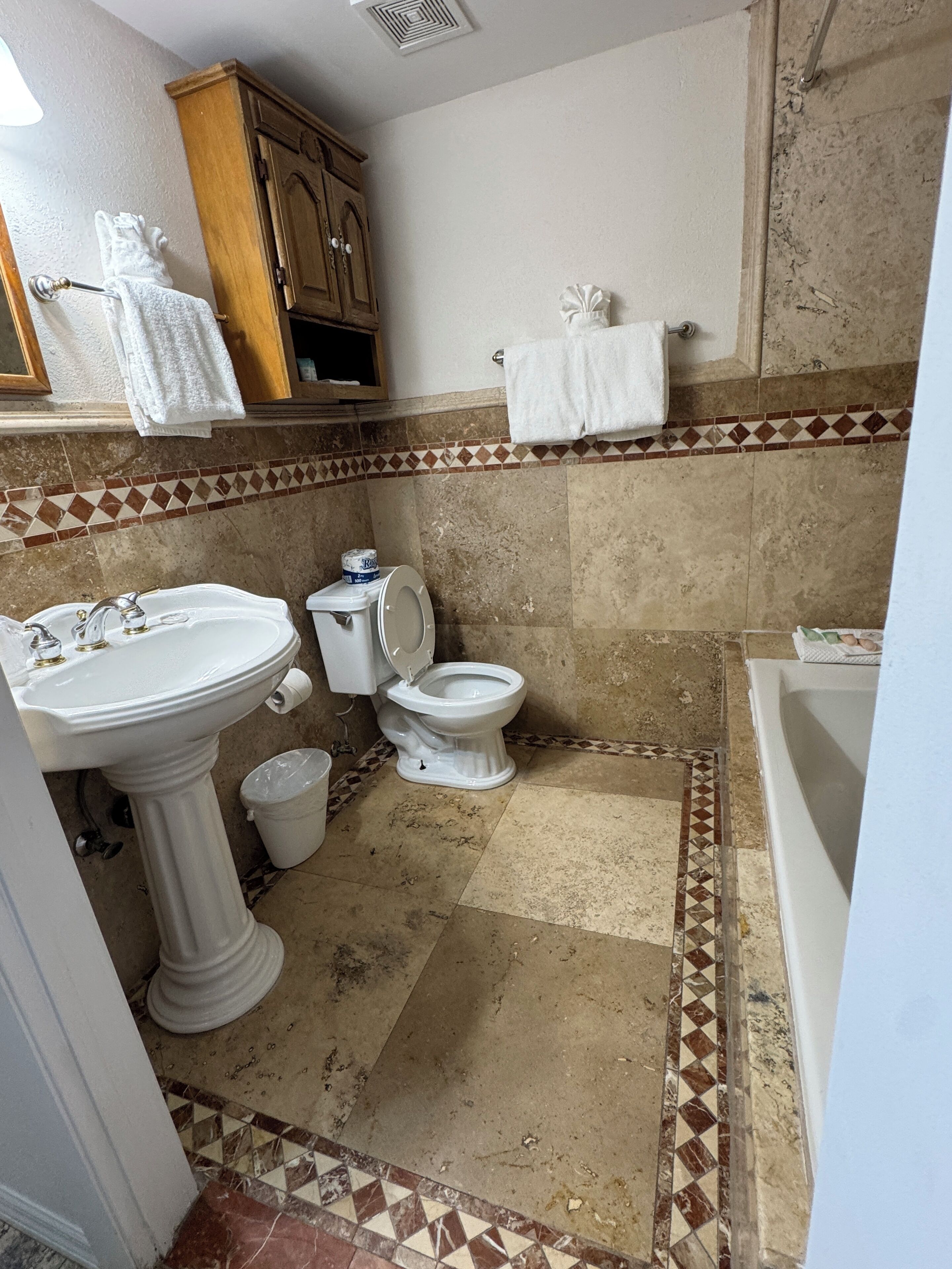 Une salle de bain avec un lavabo sur colonne, des toilettes et une baignoire.