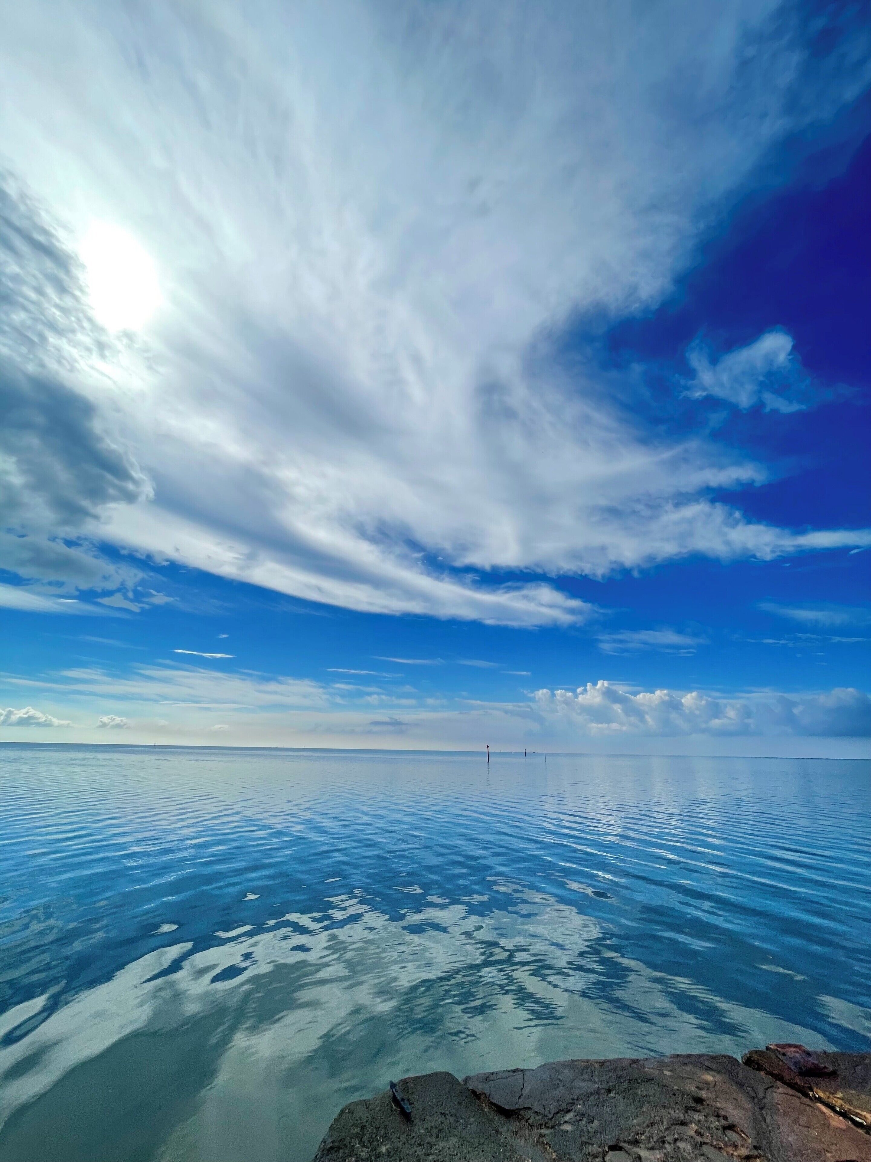 Ruhige See mit blauem Himmel und felsiger Küste.