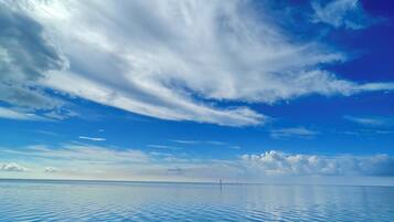 Ruhige See mit blauem Himmel und felsiger Küste.