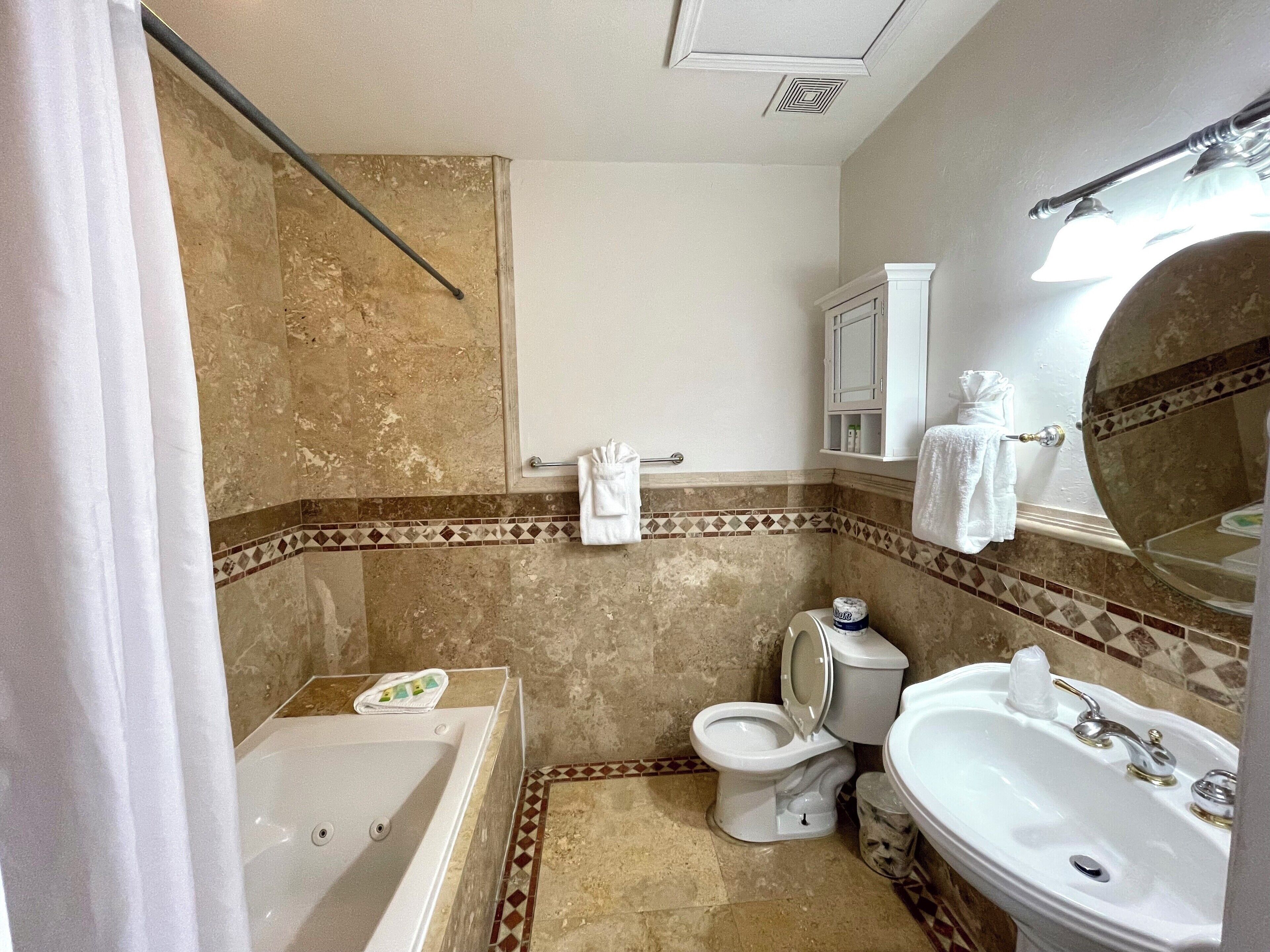 A bathroom with a bathtub, toilet, sink, and a mirror.