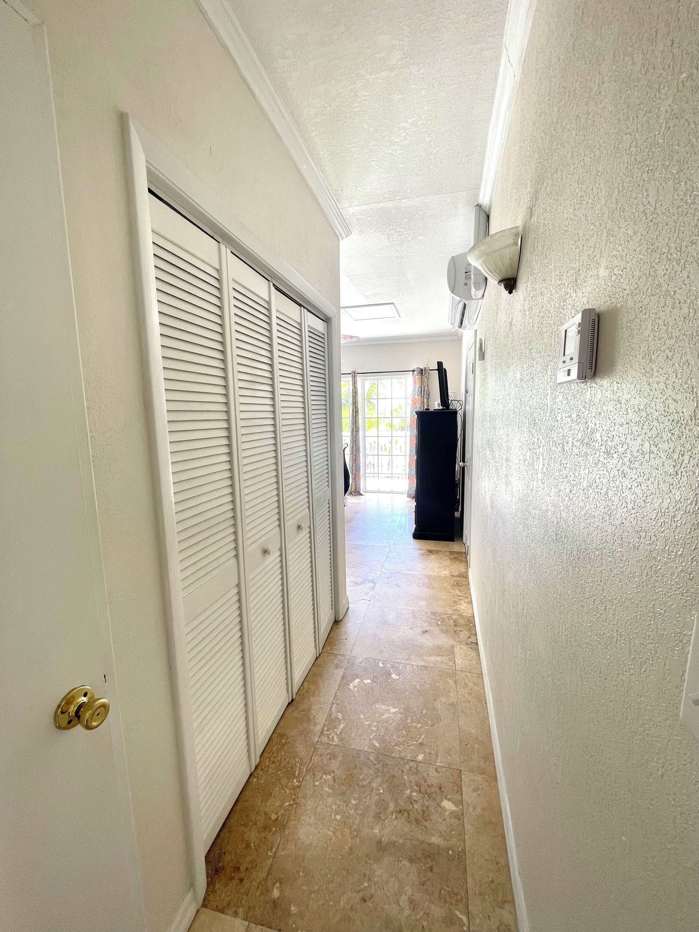 A hallway with a tiled floor, white walls, and a closed door with a golden handle.
