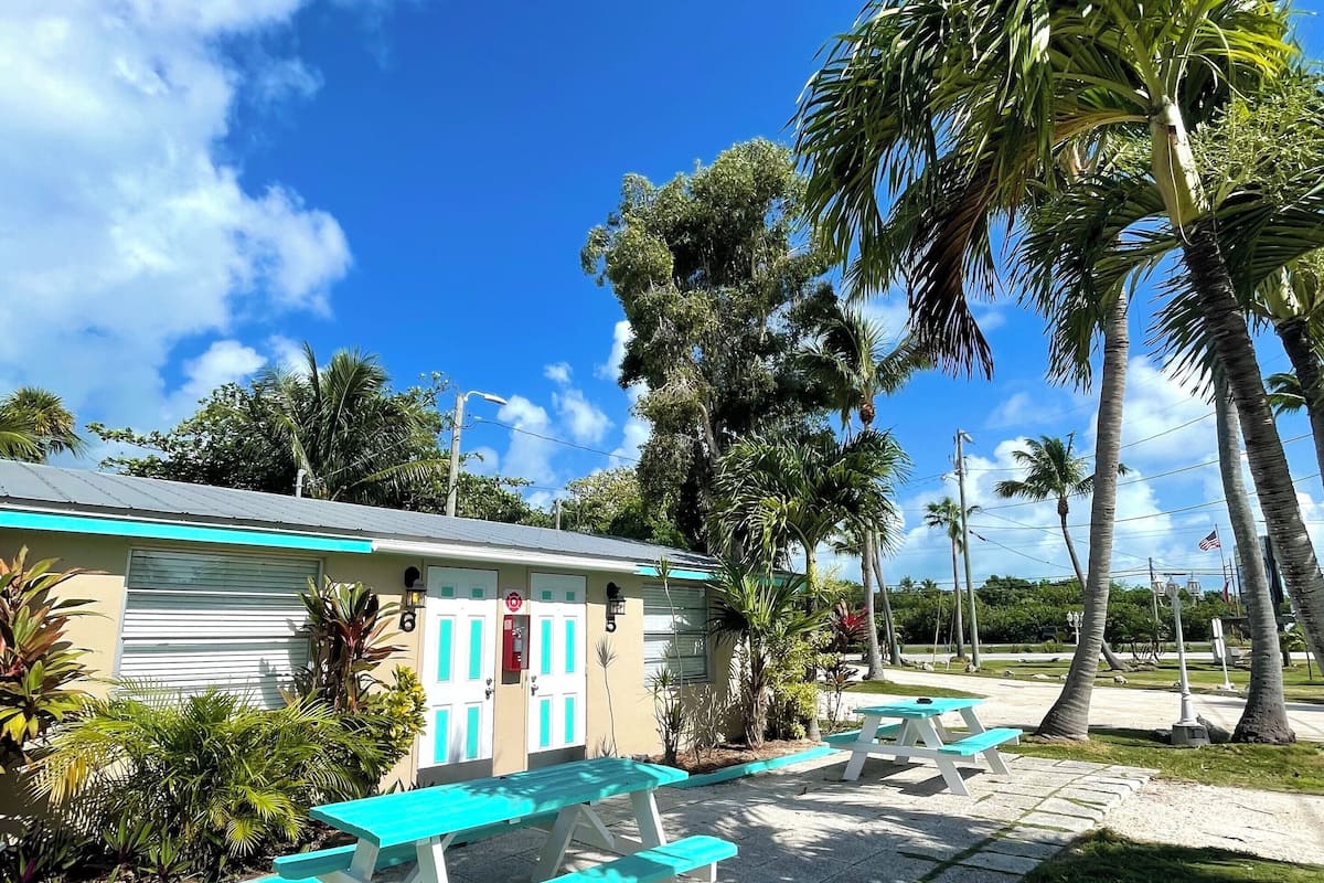 A motel with outdoor picnic tables and palm trees.