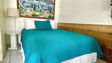 Ein Schlafzimmer mit einem Bett, einem Bild von Delfinen, einer Nachttischlampe und einem hölzernen Kopfteil.