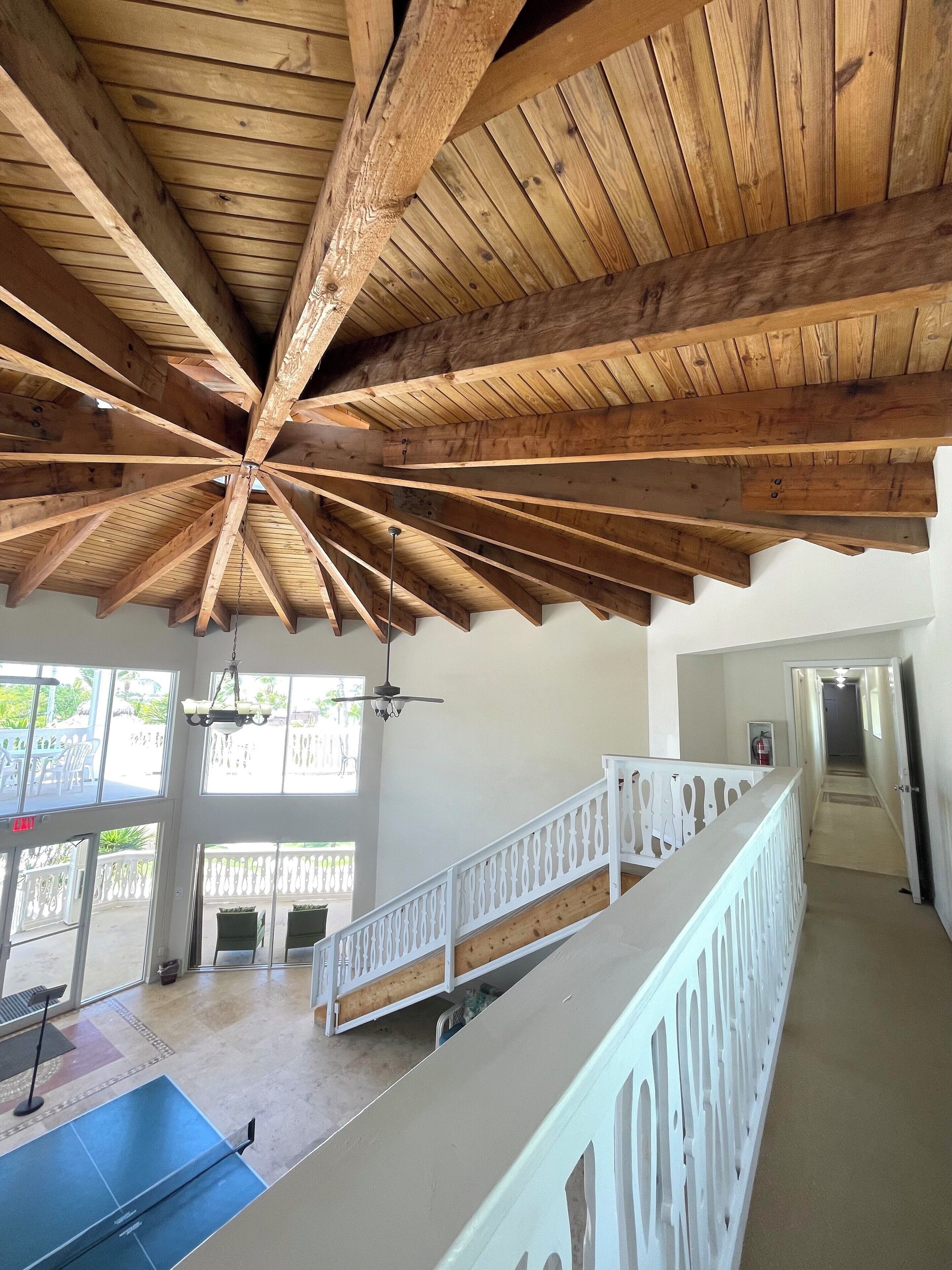 A spacious indoor area with a high wooden ceiling and a balcony railing.