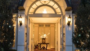 Entrada de hotel con un arco clásico, iluminada por apliques de pared y luces colgantes.