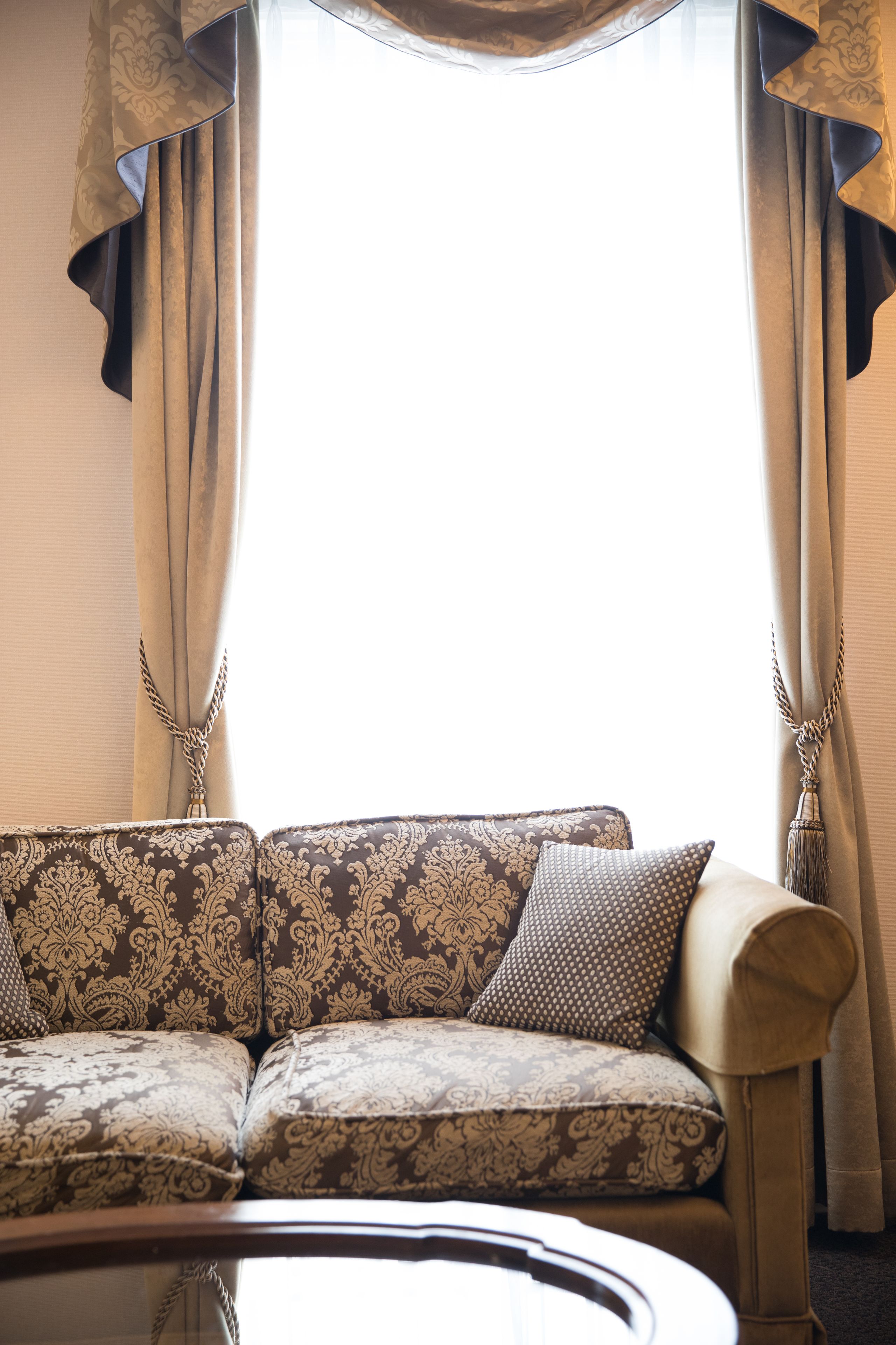 A room with a patterned sofa, a coffee table, and curtains.