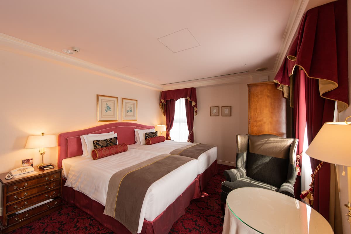 Ein Hotelzimmer mit einem großen Bett, einem Schreibtisch mit Lampe, einem Sessel und einem Schminktisch.