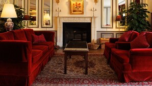 Un salón tradicional con sofás rojos, una chimenea y una alfombra estampada.