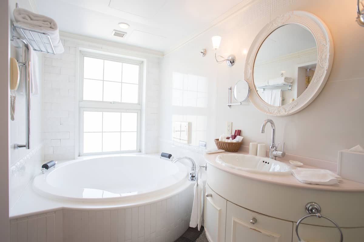 Ein modernes Badezimmer mit einer freistehenden Badewanne, einem Waschtisch mit Spiegel und einem Fenster für natürliches Licht.