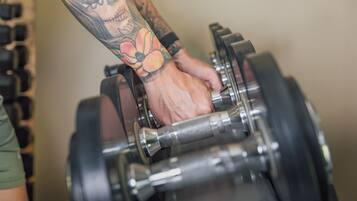A person lifting a dumbbell with a tattoo on their arm.