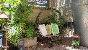Una silla colgante con cojines en un jardín con plantas en macetas y un letrero de Lennox Hotels.