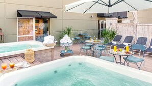 Un área de piscina en la azotea con un jacuzzi, sillones de descanso y una mesa con bebidas.