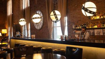 A bar area with leather stools, a bar counter, and hanging spherical light fixtures.