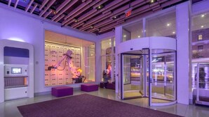 Un'accogliente hall moderna con un braccio robotico, una porta girevole e un ampio tappeto viola.