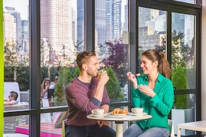 Enjoy a casual dining experience with a city view at this urban cafe, featuring a minimalist design and comfortable seating for two.