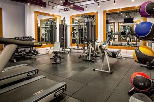 A gym with various exercise equipment, including treadmills, weight machines, and free weights.