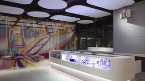 Un interno moderno con una vetrina centrale, un murales astratto e colorato e un cartello informativo ben visibile.