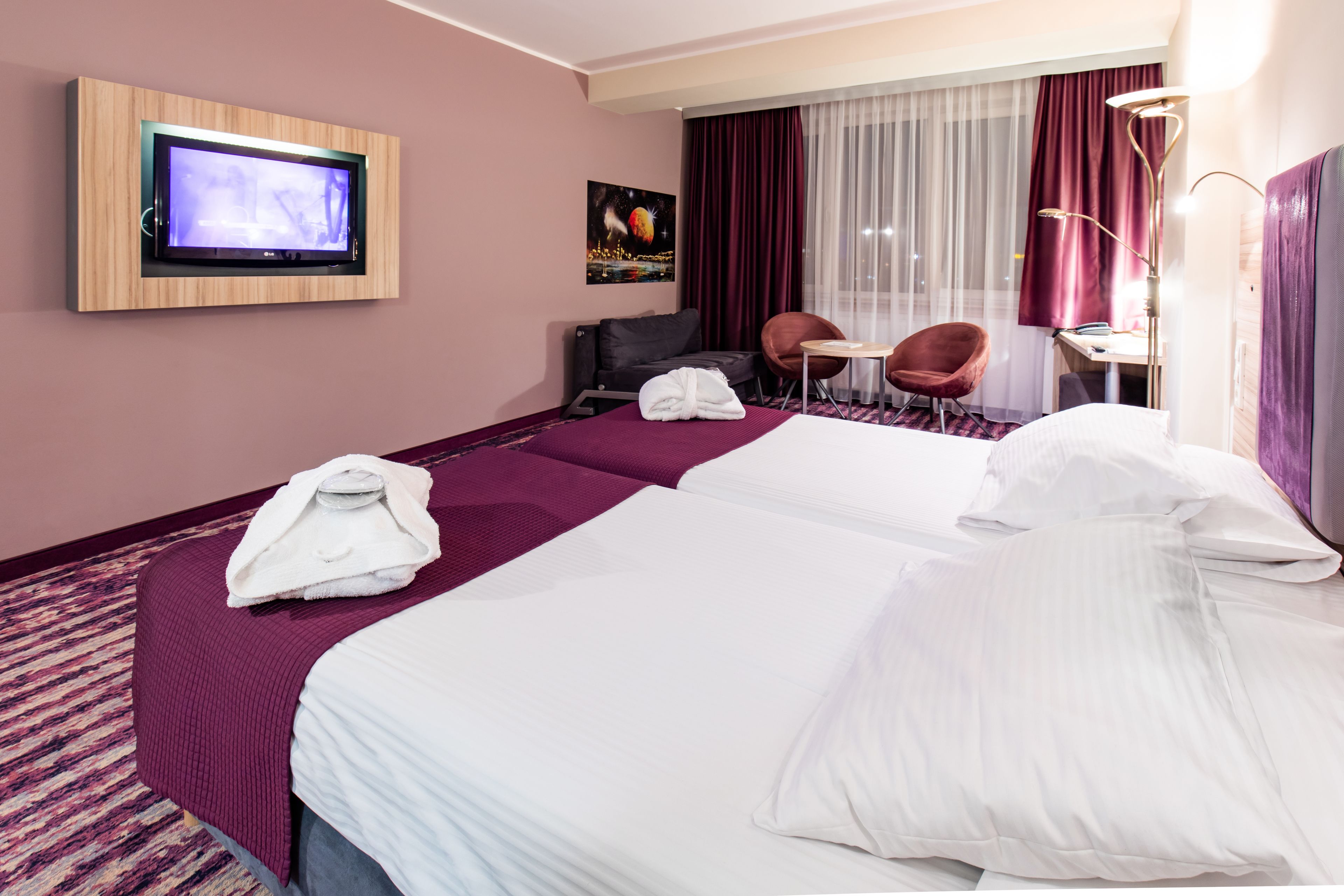 A hotel room with two beds, a television, a desk, and a chair.