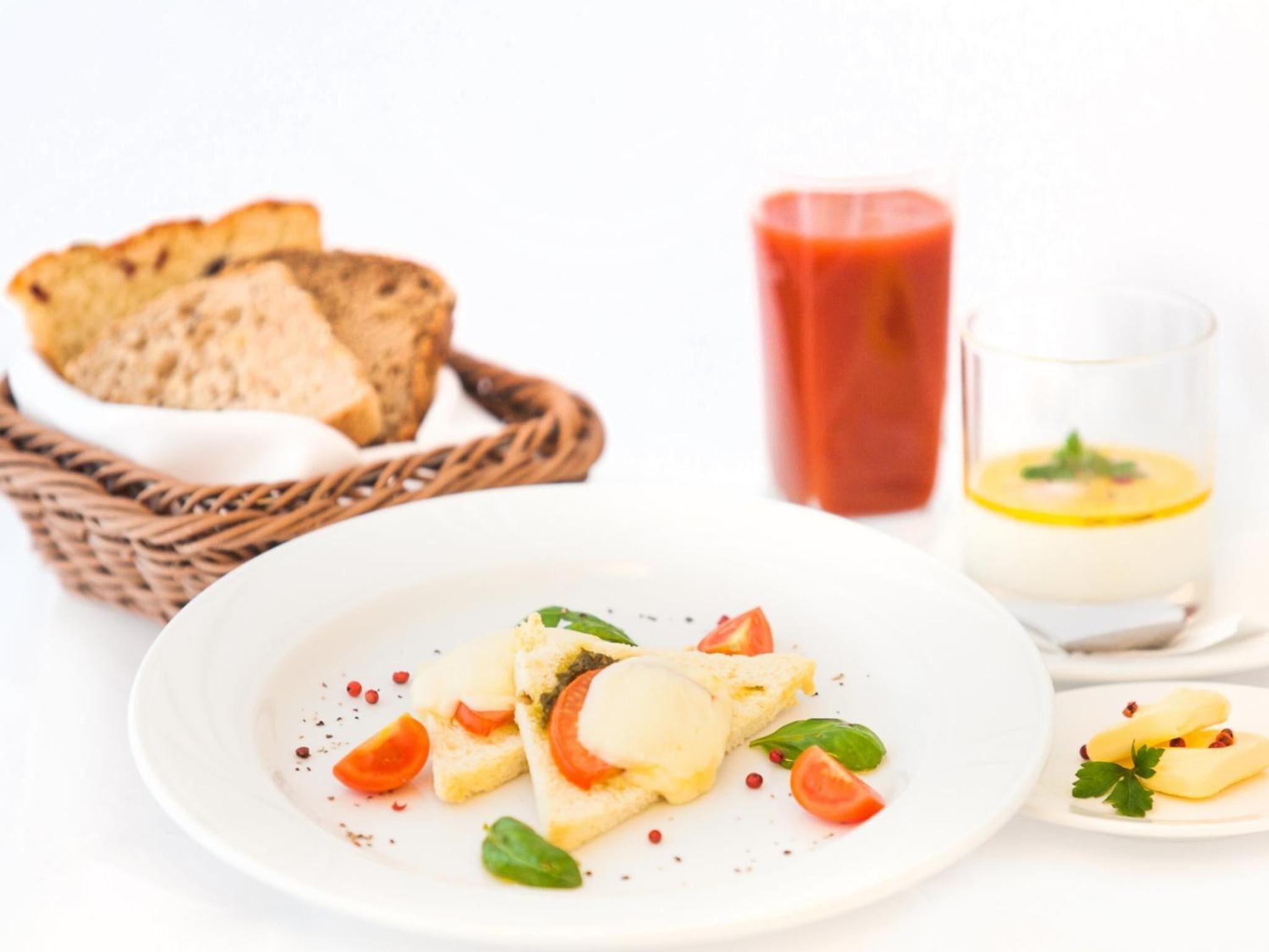 A plate of food with bread, tomatoes, and a glass of red drink.
