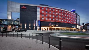 A hotel with a modern design, featuring a prominent red facade and a large sign for the Qibus Hotel.