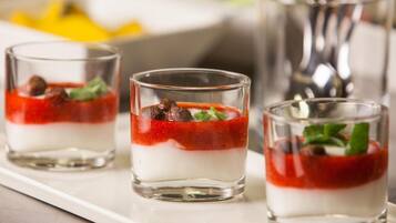 Three glasses of layered dessert with a red topping and mint garnish.