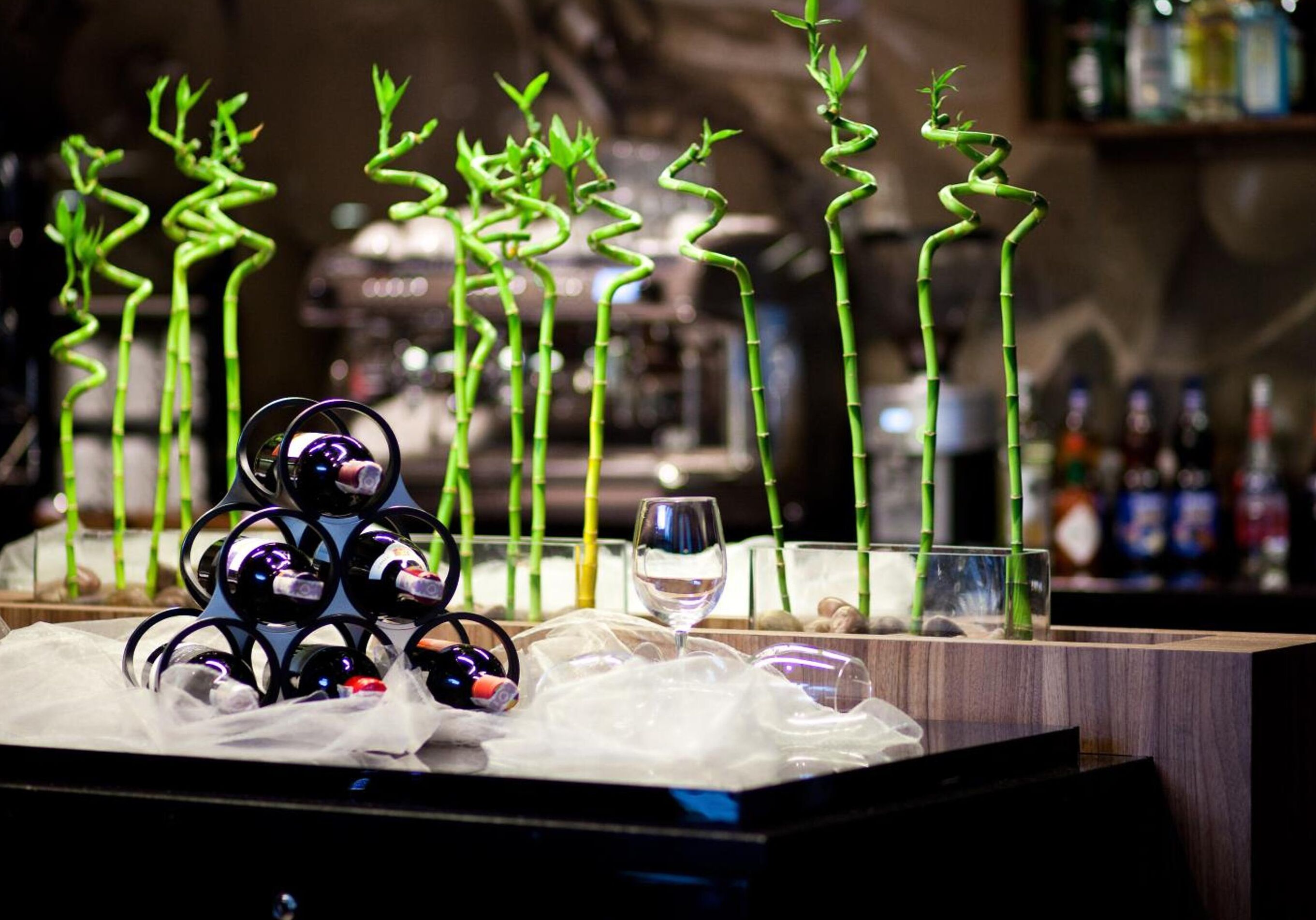 Una zona de bar con una original decoración de bambú, una estantería para vinos y una copa de vino.