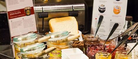 A breakfast buffet with various jams, honey, and bread.