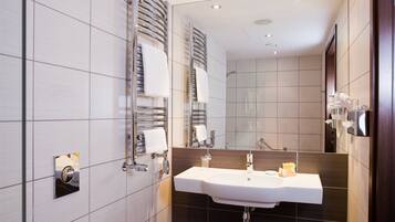 Une salle de bain moderne avec des toilettes blanches, un lavabo avec un miroir au-dessus et un espace douche.