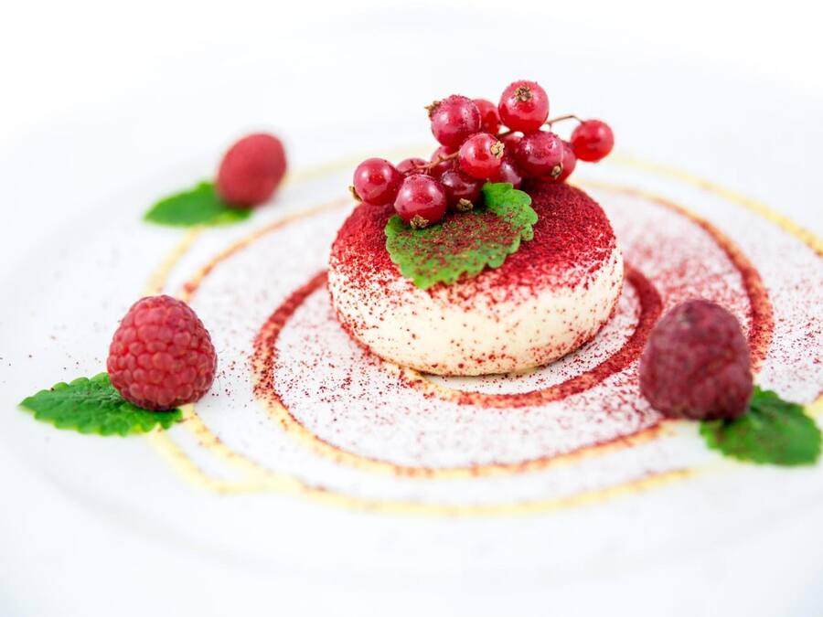 Een dessert met een framboos en bessen garnering op een wit bord.