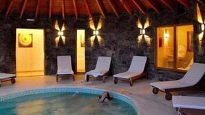 Ein Poolbereich mit Liegestühlen und einer Steinmauer.